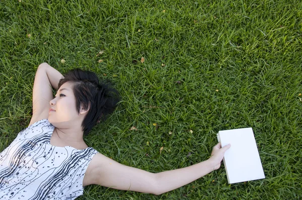 Jovem mulher lendo um livro no campo — Fotografia de Stock