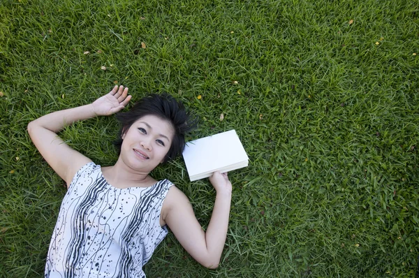 Giovane donna che legge un libro sul campo — Foto Stock