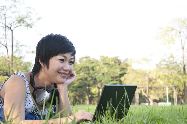 Asiática dama usando ordenador en un campo — Foto de Stock
