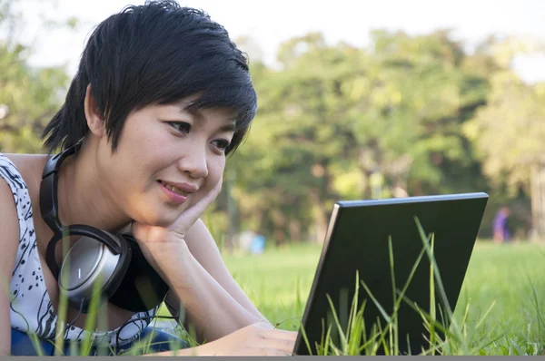 Asian lady using computer in a field — Stock Photo, Image