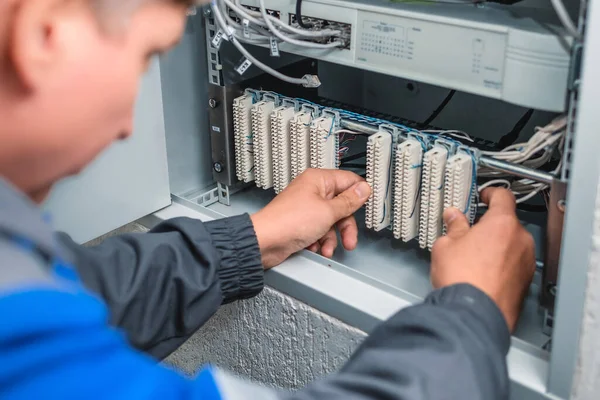 Un electricista comprueba los terminales de los equipos de comunicación telefónica. — Foto de Stock