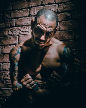 Dövmeli bir haydut ya da tecavüzcü hücre hapsinde tutuluyor. Eller kelepçeli..