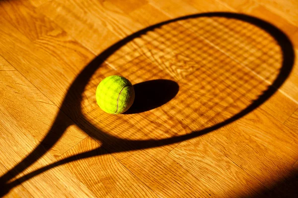 The sight of a tennis ball and the shadow on the floor from a tennis racket. background sports theme.
