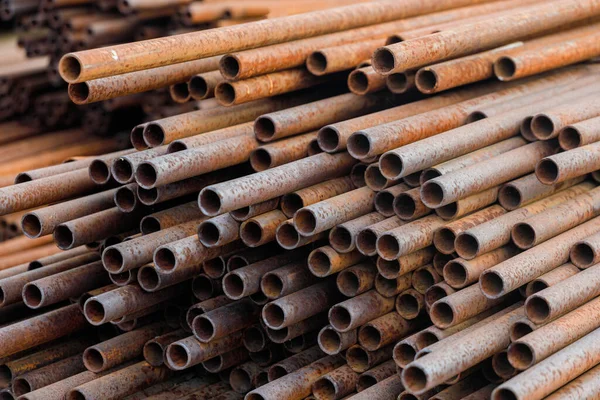 Many small-diameter metal pipes for gasification and construction lie in a stack in an open warehouse on the street.