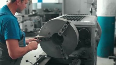 Dönüştürücü atölyedeki tornanın bakımını ve onarımını yapıyor. Yavaş çekim videosu. Orta boy..