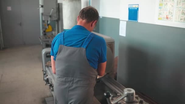 Le tourneur traite la pièce métallique sur un tour dans un atelier de tour. Vidéo au ralenti. Images de taille moyenne — Video