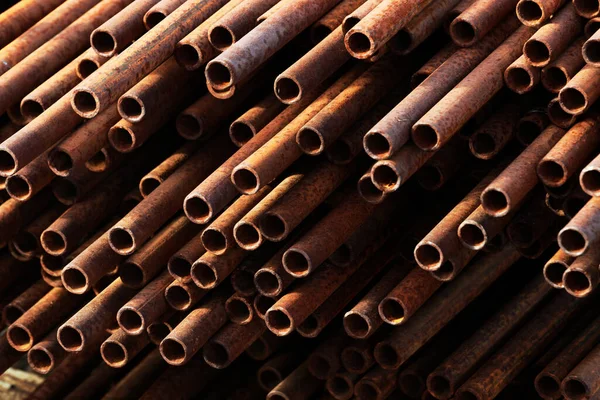 Muitos tubos de metal de pequeno diâmetro para gaseificação e construção encontram-se em uma pilha em um armazém aberto na rua. — Fotografia de Stock