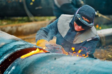Kaynakçı büyük metal boruları seksen kaynakla kesiyor..
