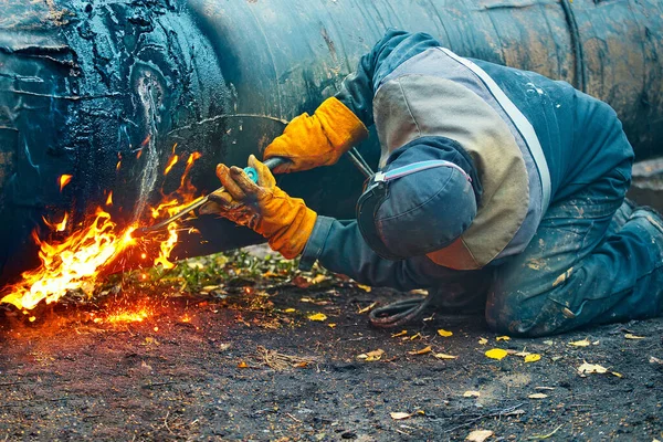 Un trabajador con ropa protectora corta un tubo de metal para la gasificación. Reparación y mantenimiento del gasoducto. —  Fotos de Stock