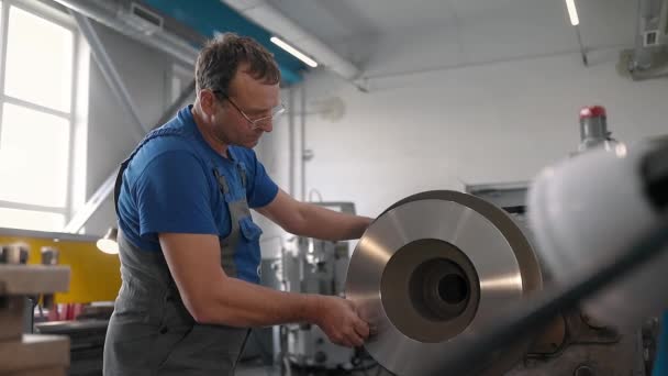 Le tourneur traite la pièce métallique sur un tour dans un atelier de tour. Vidéo au ralenti. Images de taille moyenne — Video