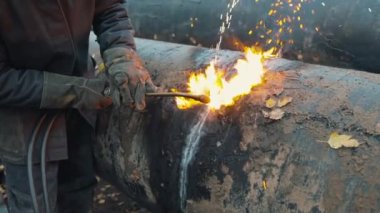 Kaynakçı gaz için asetilen kaynakla büyük bir boru kesiyor. Kullanılmış metal boruların imhası.