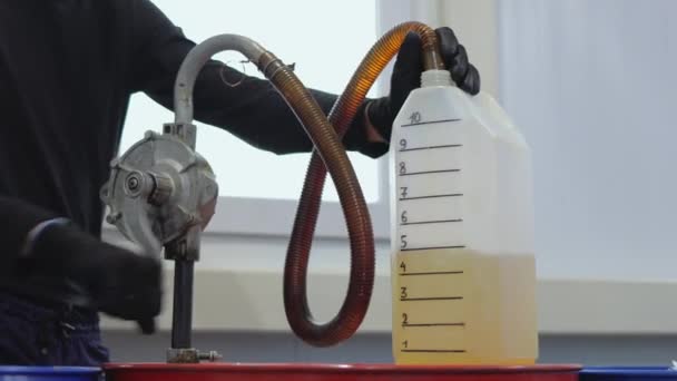 Відео 4k. Працівник АЗС наповнює моторну олію ручним насосом у вимірювальну каністру. Крупним планом . — стокове відео