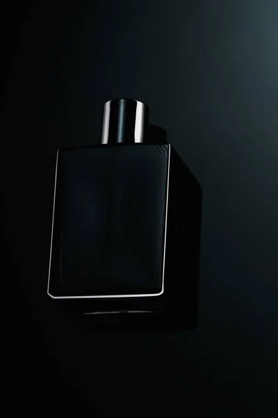 Silhuett av en svart flaska eau de toilette för män på en mörk bakgrund. Reklam foto av parfymer. Mörk stil — Stockfoto