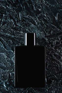 Siyah bir şişe Eau de Tuvalet 'in silueti. Siyah arka plandaki erkekler için. Parfümlerin reklam fotoğrafı. Koyu renk