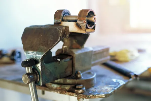 Kovový výrobek je mačkán ve svěráku na pracovišti v dílně. — Stock fotografie