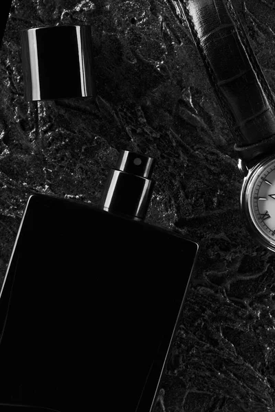 Relojes para hombre y una botella abierta de Eau de toilette negro se encuentran sobre un fondo de textura oscura. Fragancia para hombres. —  Fotos de Stock