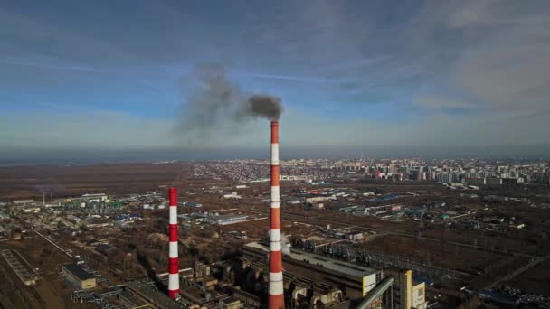 Uitzicht op de stad van bovenaf tegen de achtergrond van de leidingen van de thermische centrale van waaruit er rook is. — Stockvideo