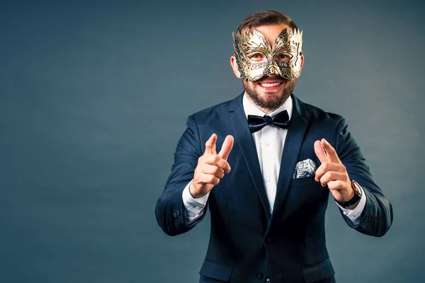 Portrait of man in carnival mask on gray homogeneous background. Face under mask.