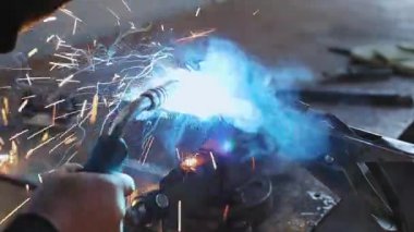 Kaynakçı kısmı, metal mengeneye sıkıştırılmış tezgah ve kıvılcımlar uçuşuyor. Yüksek çözünürlüklü video. Gerçek sahne.