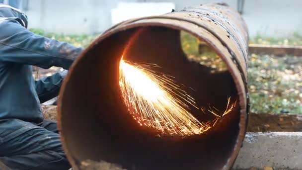 Сварщик режет металлическую трубу большого диаметра и искры летят. — стоковое видео