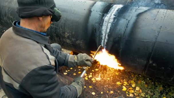 Сварщик на работе режет металлическую трубу. Ремонт газопровода. Подлинное непостановочное видео. — стоковое видео