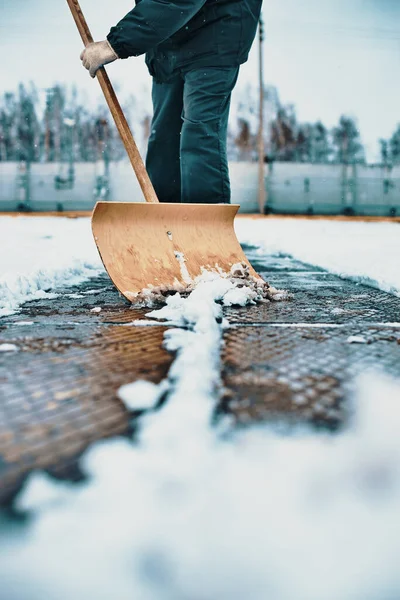 El conserje limpia el área de nieve con una pala de madera. Limpieza de calles después de nevadas y ventiscas. — Foto de Stock