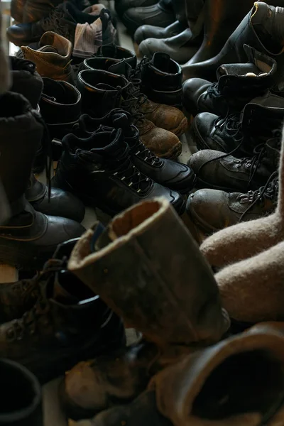 Muitas botas de trabalho velhas estão juntas. Velhas botas de construção usadas de trabalhadores. Cena real. Deslocar sapatos. — Fotografia de Stock