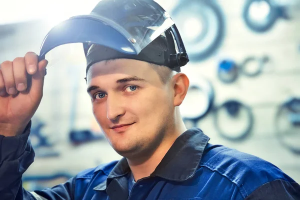 Fémlakatos portréja. A fiatal kaukázusi férfi a védőmaszk alól néz a kamerába. Valódi munkavállaló — Stock Fotó