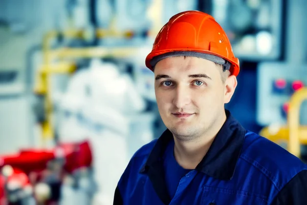 Retrato de joven ingeniero en casco en el entorno de trabajo en la factoría. trabajador de gas con confianza mira directamente a la cámara — Foto de Stock
