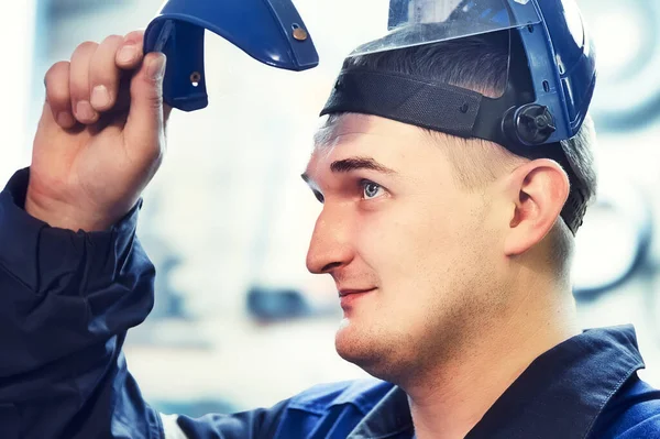 Portrait of metalworker or worker. Young Caucasian looks from under visor of protective mask. Real worker — Stockfoto