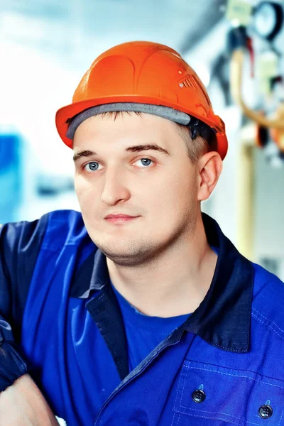 Retrato de joven ingeniero en casco en el entorno de trabajo en la factoría. trabajador de gas con confianza mira directamente a la cámara — Foto de Stock