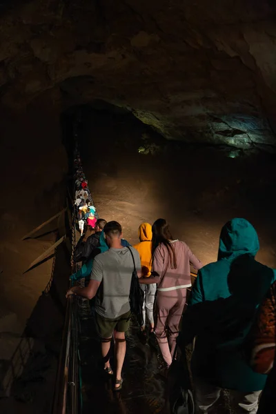 5 julio 2018 Nuevo Athos, Abjasia: Grupo de turistas cruza un puente colgante en una enorme cueva. Imagen editorial — Foto de Stock