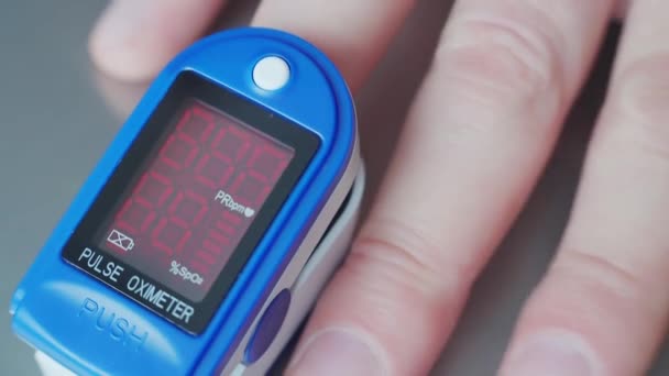 Close-up video. Doctor measures saturation through finger with electronic device with display. Static frame. — Stock Video