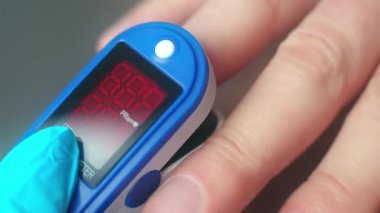 Yakın çekim video. Doktor, ekranlı elektronik cihazla parmak yoluyla doygunluğu ölçer. Sabit çerçeve.