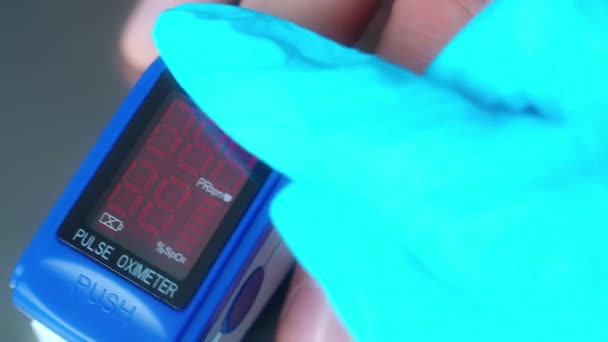 Close-up video. Doctor measures saturation through finger with electronic device with display. Static frame. — Stock Video