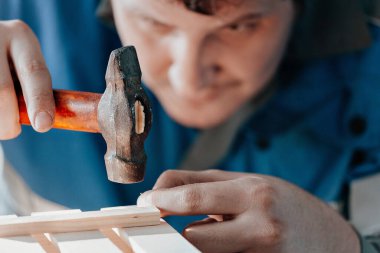 İş kıyafetleri içindeki genç beyaz marangoz marangozluk atölyesinde ahşap kutular yapıyor. Gerçek sahne. Küçük işletme