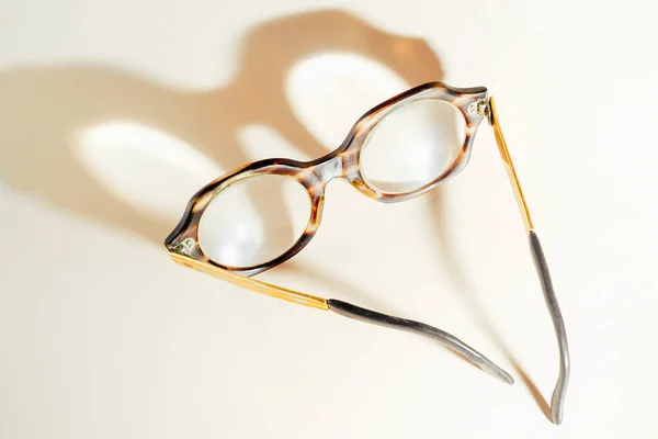 Γυαλιά για ηλικιωμένους βρίσκονται σε μπεζ φόντο και ρίχνει σκιά.Άποψη από τα πάνω. — Φωτογραφία Αρχείου