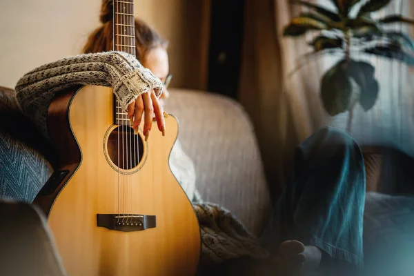 Genç kız kanepede gitar ile oturuyor. Ergen, müzik aleti olan bir hipster.. — Stok fotoğraf