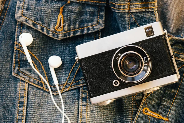 필름 카메라 와 흰 유선 헤드폰 은 데님 을 배경으로 놓여 있다. 유행하는 히프 스터 배경. 역 스타일. — 스톡 사진