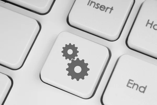 Cogwheels on white keyboard — Stock Photo, Image