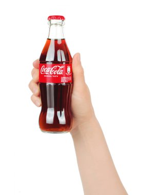 Kiev, Ukrayna - 25 Mayıs 2022: Beyaz arka planda Coca-Cola şişesiyle el ele. Coca-Cola, Coca-Cola Company tarafından üretilen bir alkolsüz içecek.