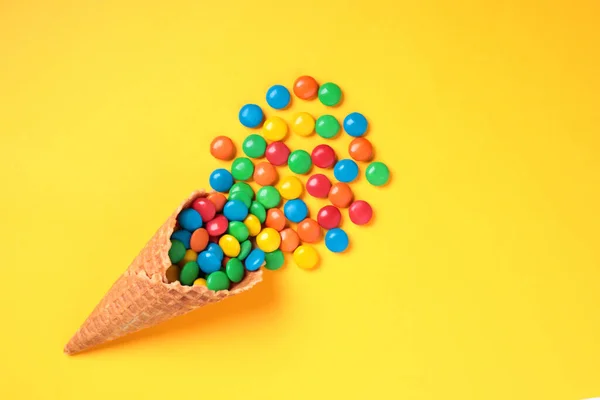 黄底特写上彩色糖果的华夫圆锥 — 图库照片