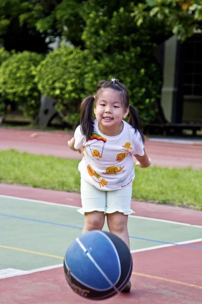 Ejercitando poco linda chica con baloncesto — Foto de Stock