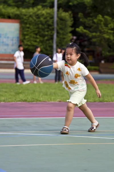 Ejercitando poco linda chica con baloncesto — Foto de Stock