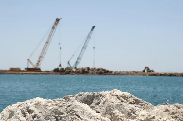 Building a dike. Cranes and excavator put stones — Stock Photo, Image