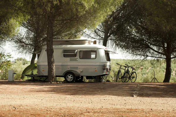 Small white caravan through the trees — Stock Photo, Image