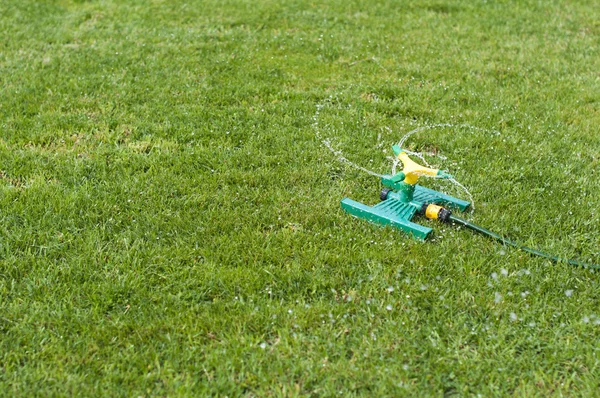 Разбрызгиватель лужайки на зеленой траве — стоковое фото