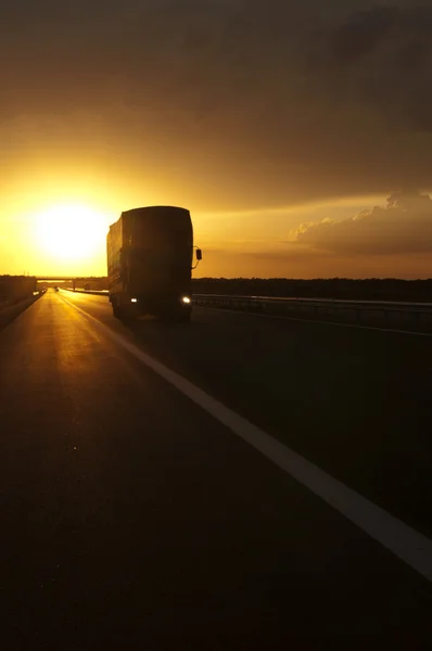 Caminhão viajando ao pôr do sol — Fotografia de Stock