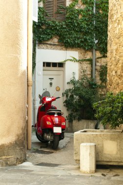 Small scooter parked at the old quarter buildings clipart