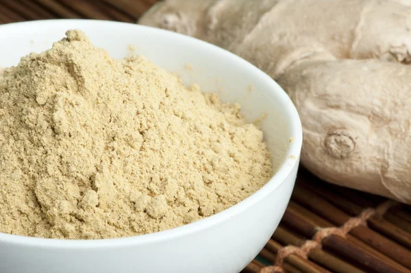 Powdered ginger in a bowl and whole ginger — Stock Photo, Image